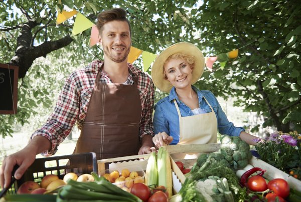 Close up of man and woman with baskets of produce from their garden