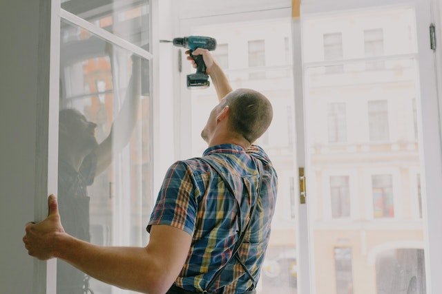 man with drill installing window frame