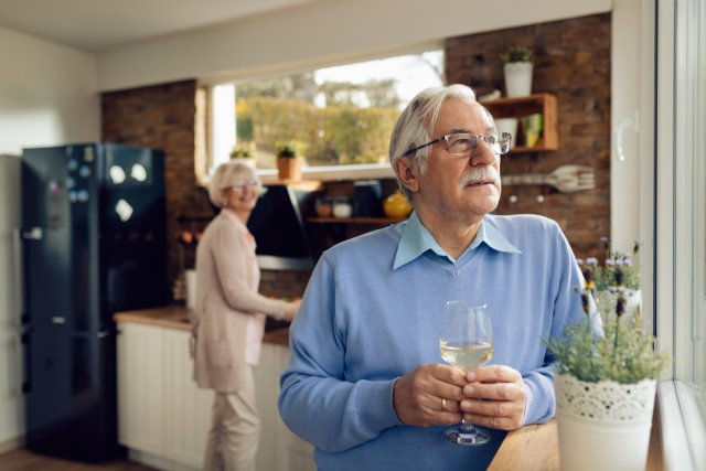 older man drinking wine in the kitchen