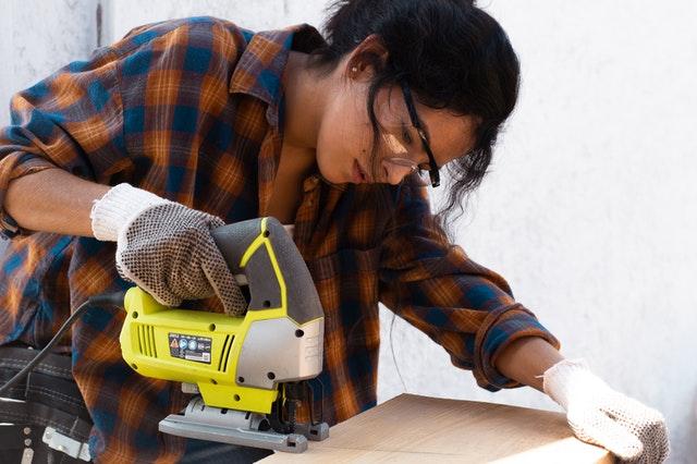 woman cutting wood with power saw
